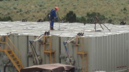 Oil field technician gauging a flowback tank. Workers check such tanks several times an hour, during which many are exposed to potentially dangerous amounts of the carcinogen benzene. (NIOSH)