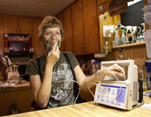 Lynn Buehring wears a respirator outdoors to keep from becoming overwhelmed by the fumes that envelop her home